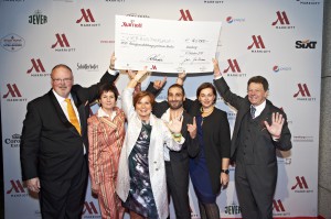 Scheckübergabe des Marriotts an SOS Kinderdorf: General Manager Peter van Rossen, Sabine Rahmel (General Manager, Köln Marriott), Elke Tesarczyk (Vorstandvorsitzende SOS-Kinderdorf Stiftung), Sänger Volkan Baydar, Gitta Brückmann (Area Vice President Central Europe, Marriott) und Burkhard Schäfer (Leiter des SOS-Berufsausbildungszentrum Berlin, SOS Kinderdorf). 