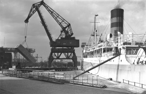 Das Foto mit dem einzelnen Kran stammt aus dem Jahr 1939. Es zeigt den 40-Tonnen-Doppellenker-Wippkran auf dem Rosshöft (Rosshafen). Dieser stand ursprünglich im Altonaer Hafen und wurde mit der Eingemeindung Altonas im Rahmen des Groß-Hamburg-Gesetzes von 1937 hierher versetzt. (Fotos: HHLA, Gustav Werbeck)