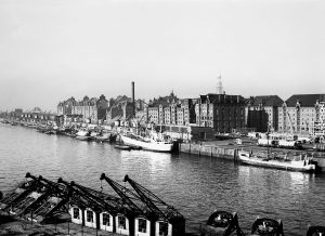 Sandtorhafen historisch:  Seit Jahrhunderten hatten die Schiffe in Hamburg an Pfählen in der Elbe, den sogenannten Duckdalben, festgemacht. Der Sandtorkai, nach Plänen des Wasserbauinspektors Johannes Dalmann entworfen, war mit seiner Eröffnung 1866 der erste seeschifftiefe Kai des Hamburger Hafens, das heißt, an ihm konnten Schiffe direkt anlegen. Die Ladung wurde mit Dampfkränen gelöscht und konnte sofort in den dahinterliegenden Schuppen gelagert, sortiert oder auf die Eisenbahngleise verbracht werden. 